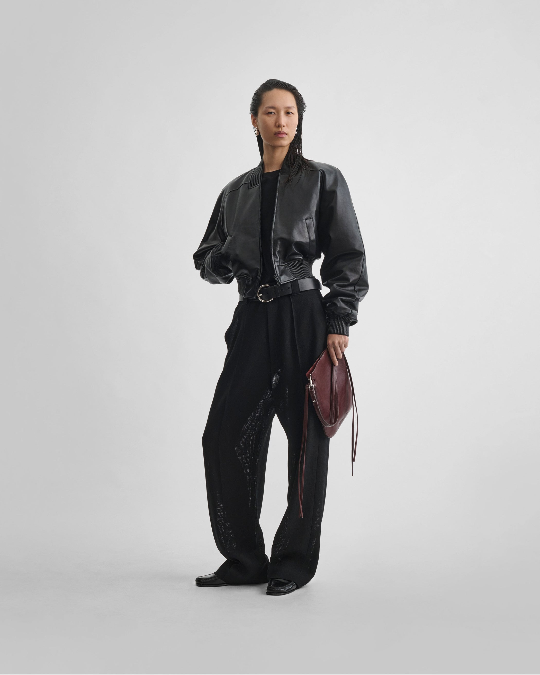 Front view of model wearing GIG POUCH BAG in oxblood leather