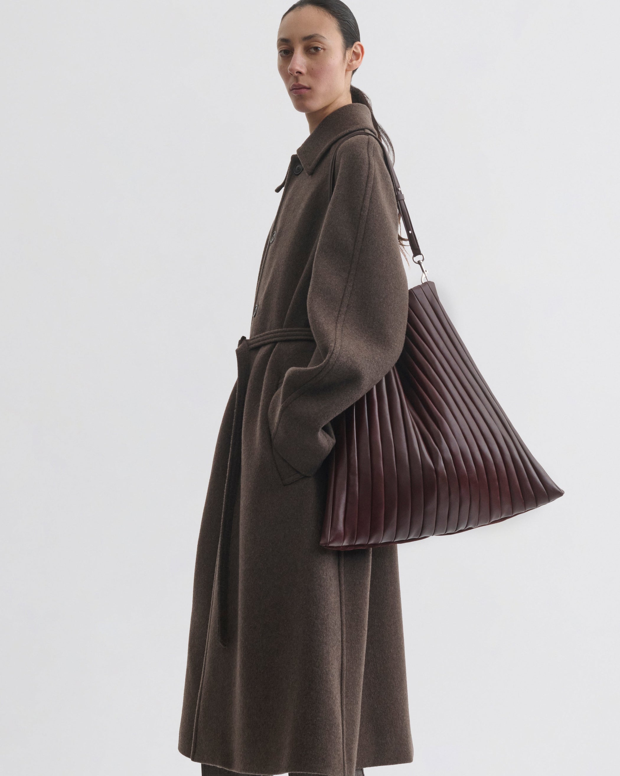 Side view of model wearing ACCORDION BAG in oxblood leather