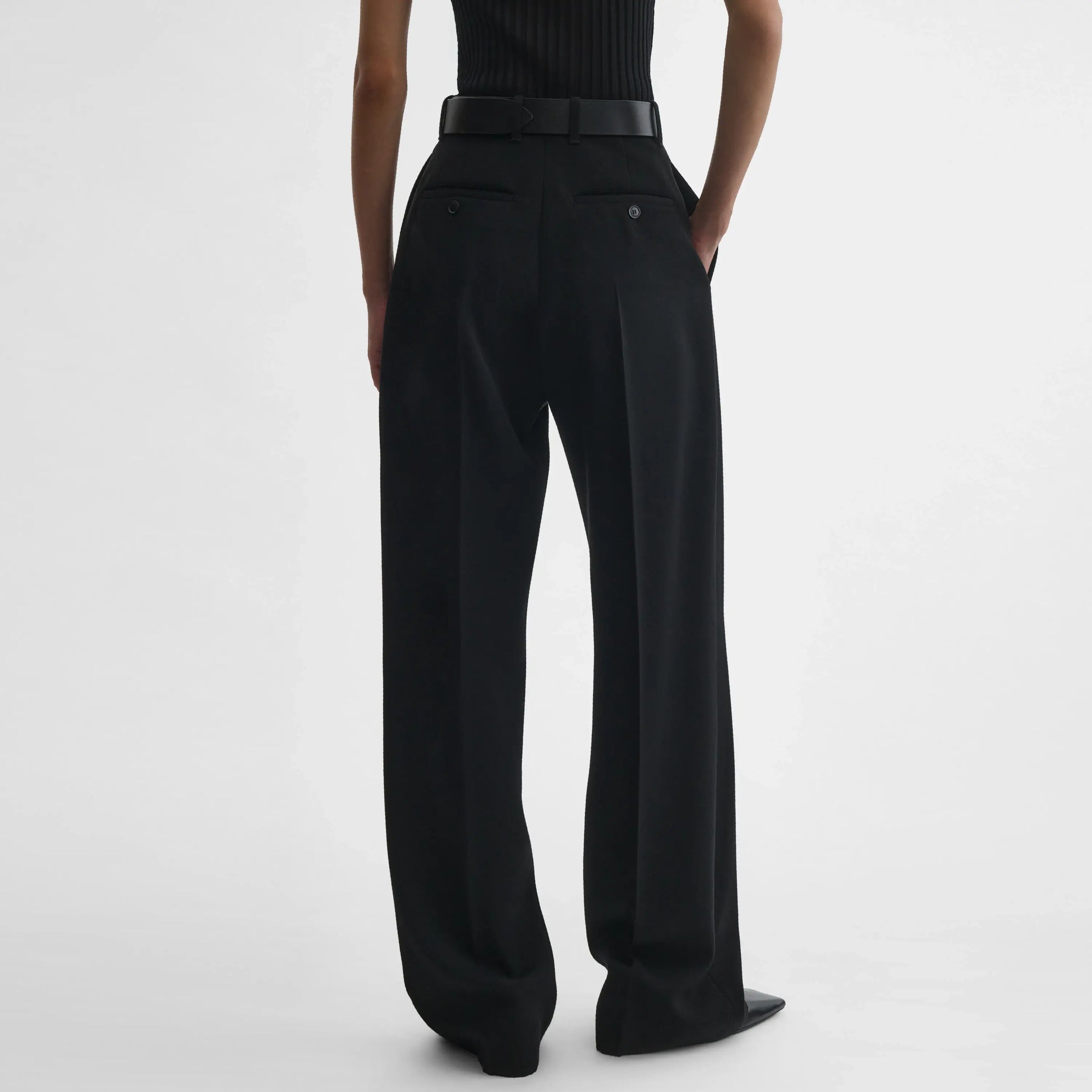 Back view of model wearing milanese trousers in black wool.