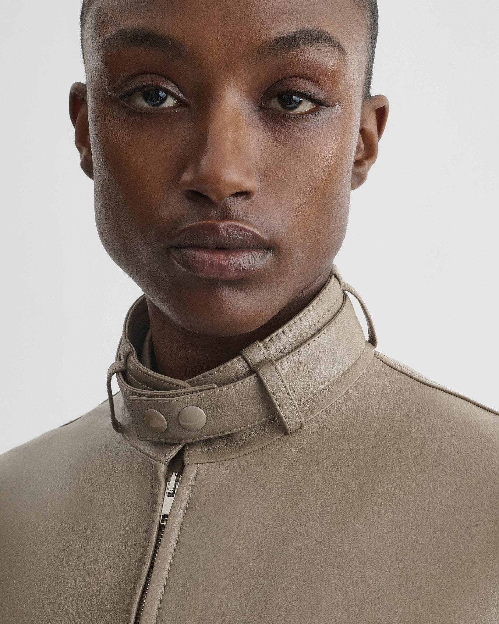 Close up detail view of model wearing jacket with attachable scarf in mastic leather