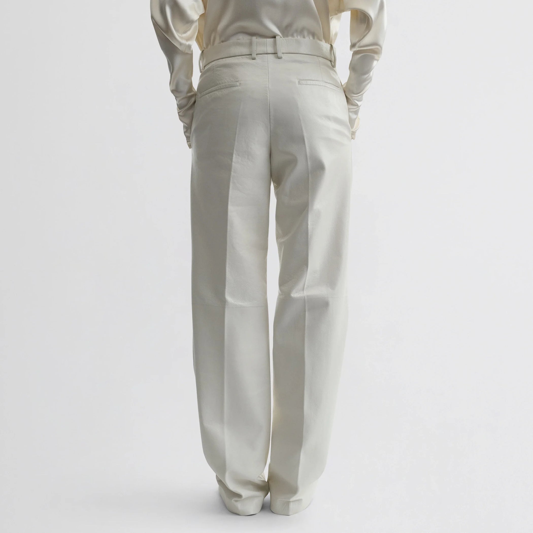 Back view of model wearing boyish trousers in white leather.