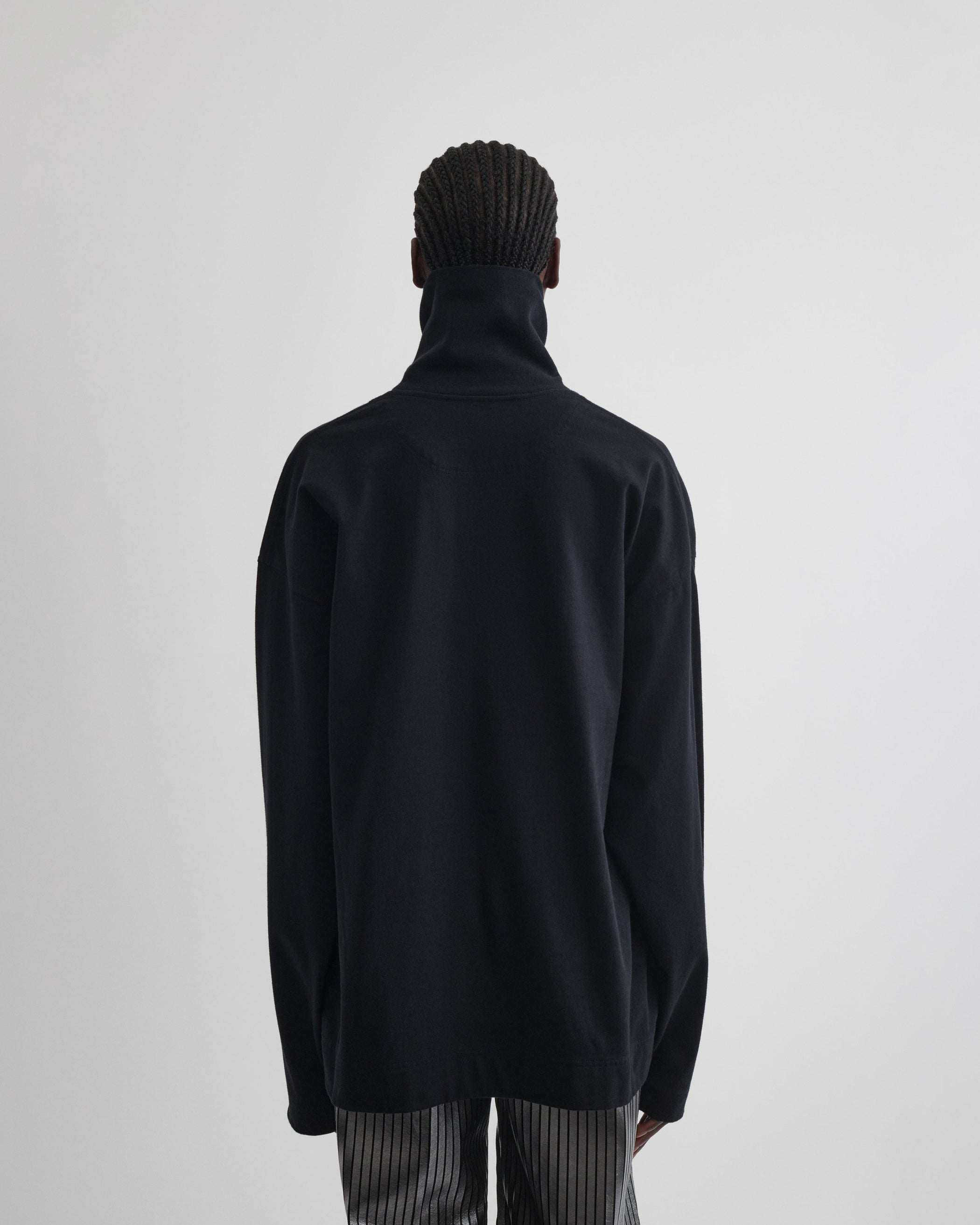 Back view of model wearing RELAXED LONG SLEEVE JERSEY in black cotton jersey