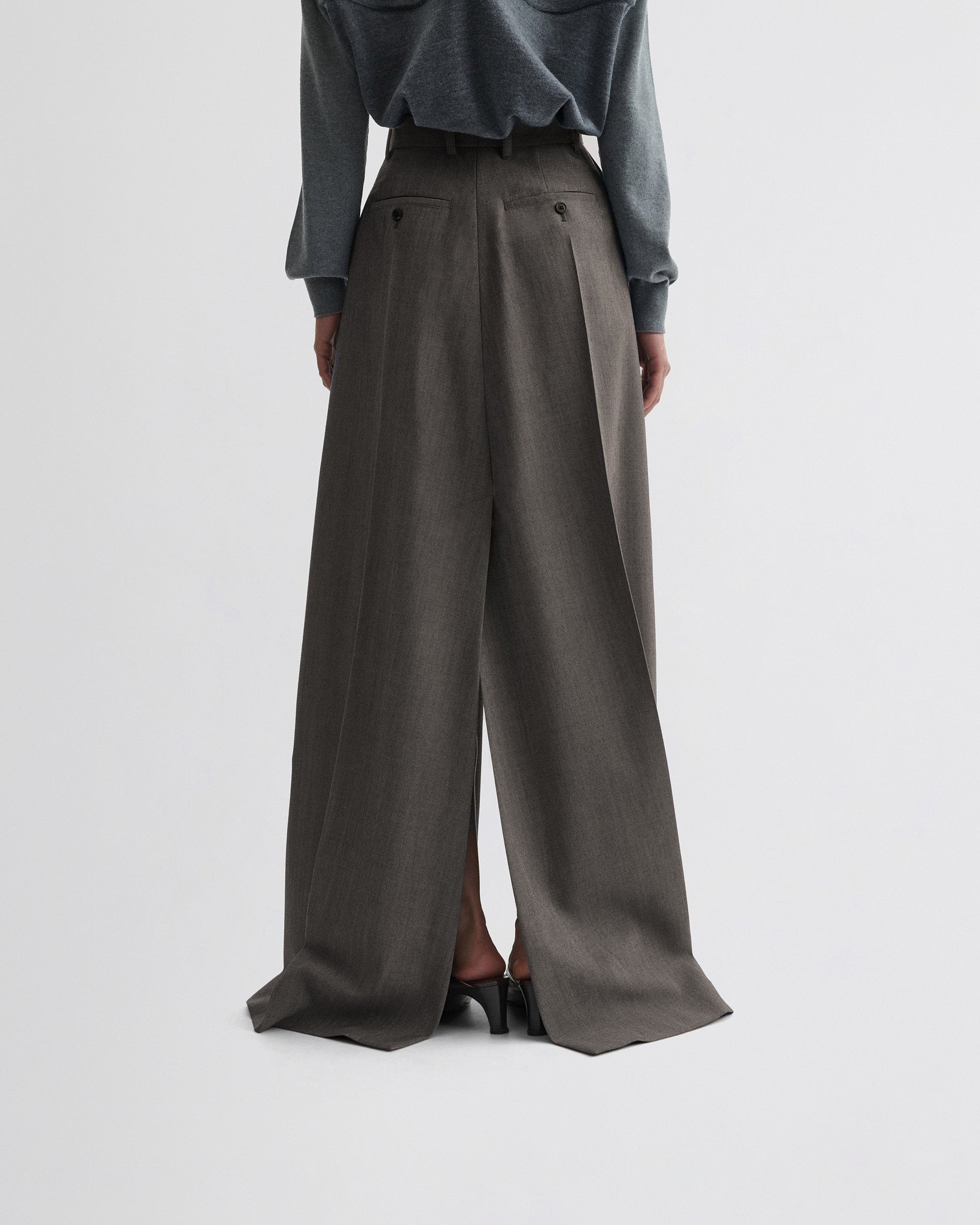 Back view of model wearing double slit tailored skirt in dark taupe wool.