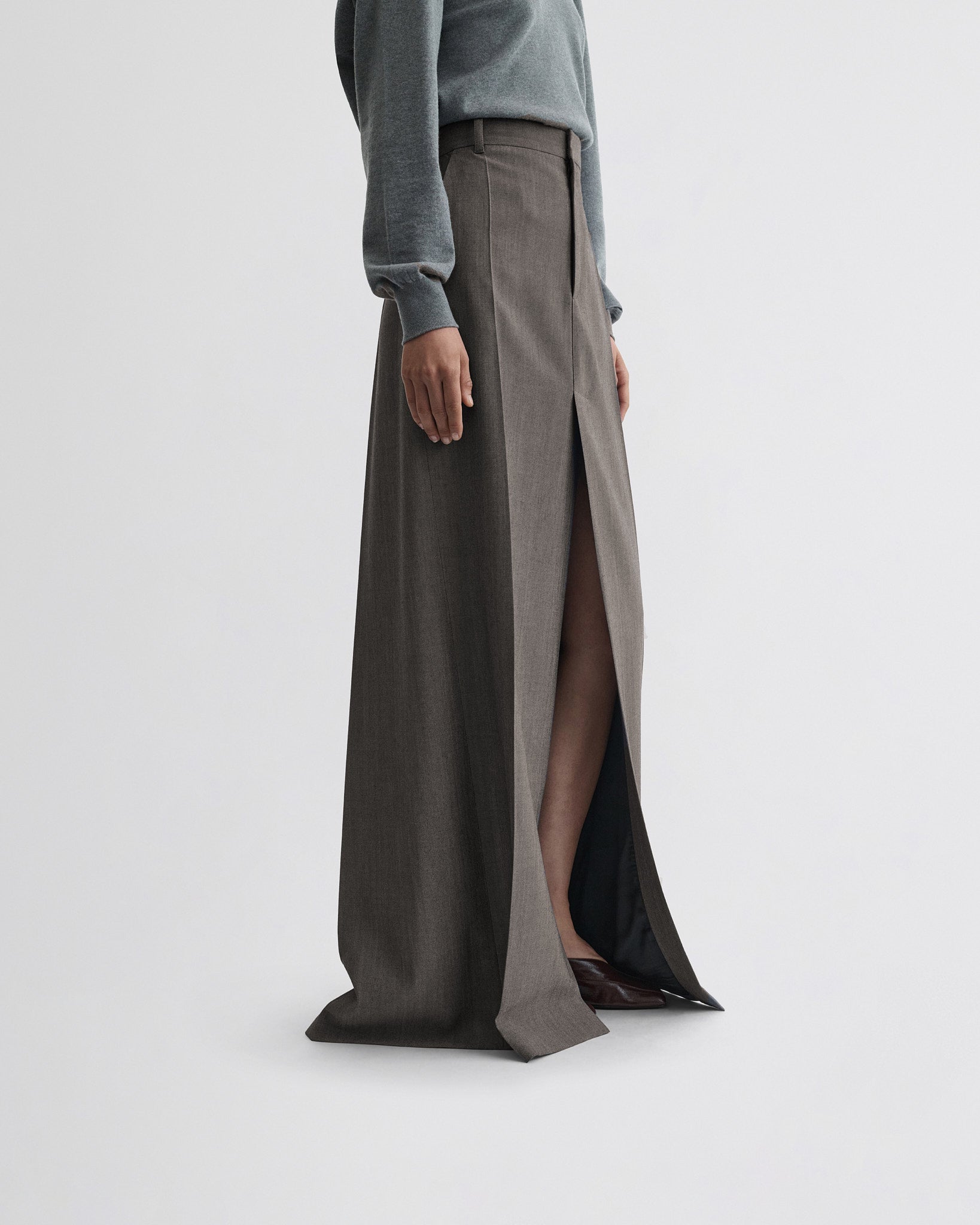 Side view of model wearing double slit tailored skirt in dark taupe wool.