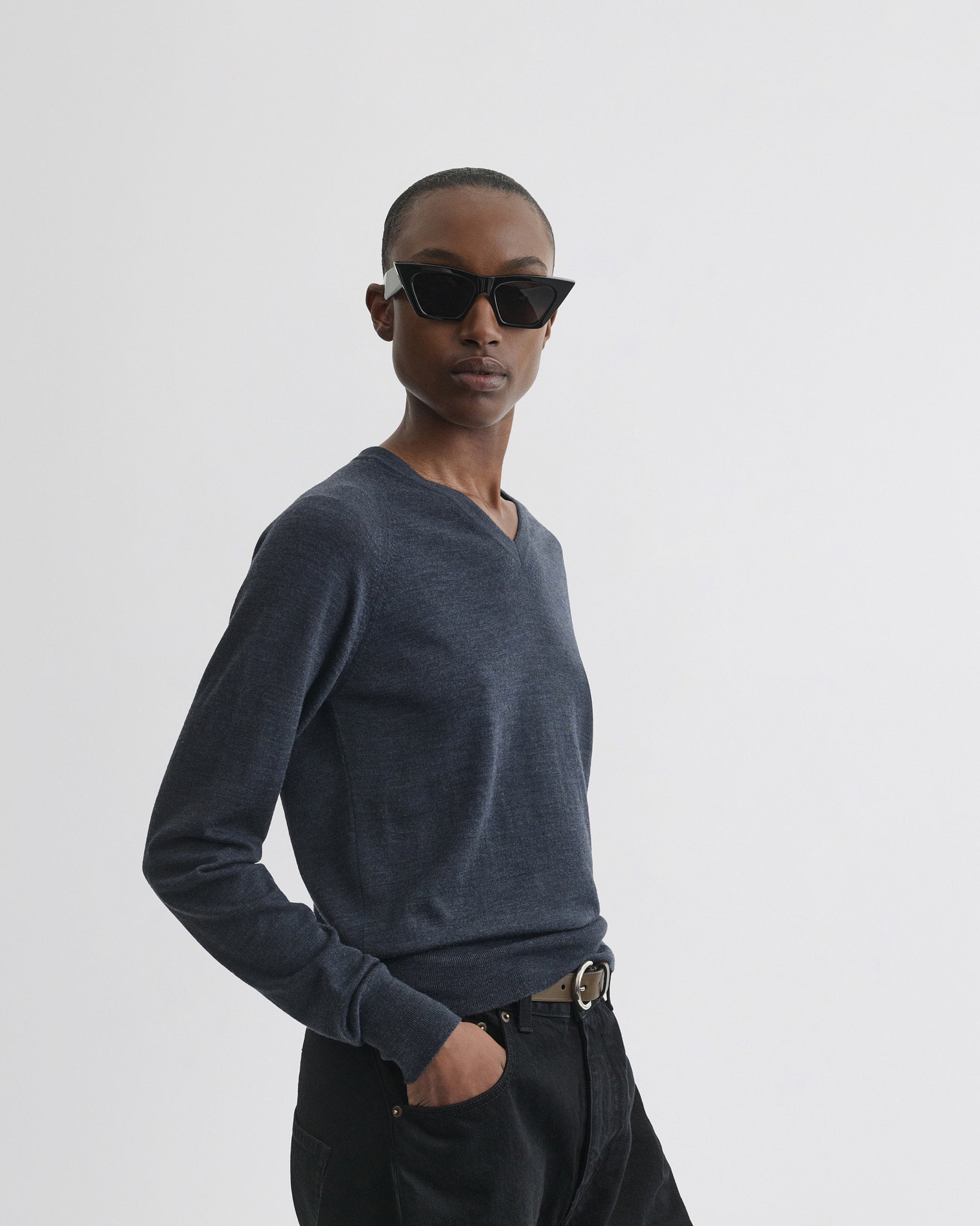 Side view of model wearing shrunk v-neck in dark blue melange wool.