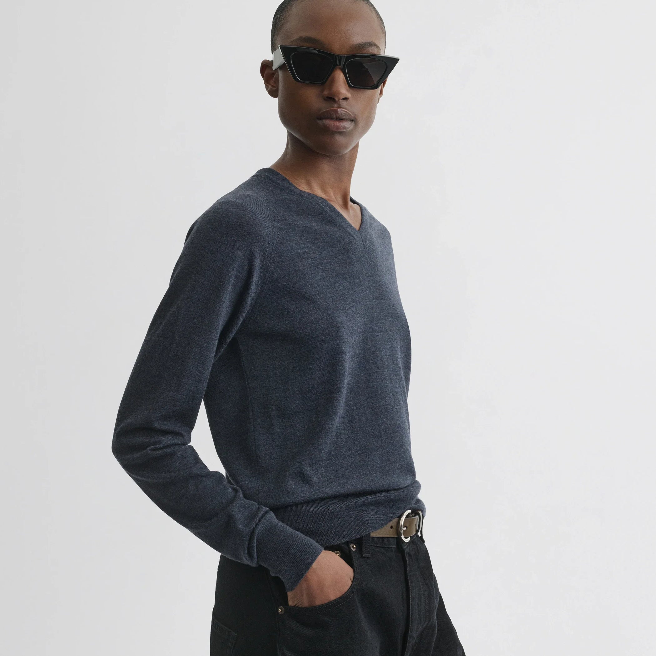 Side view of model wearing shrunk v-neck in dark blue melange wool.