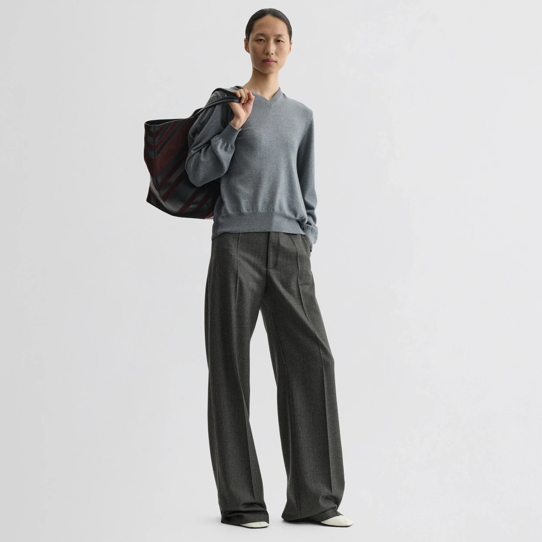 Front view of model wearing backed v-neck sweater in light grey wool.