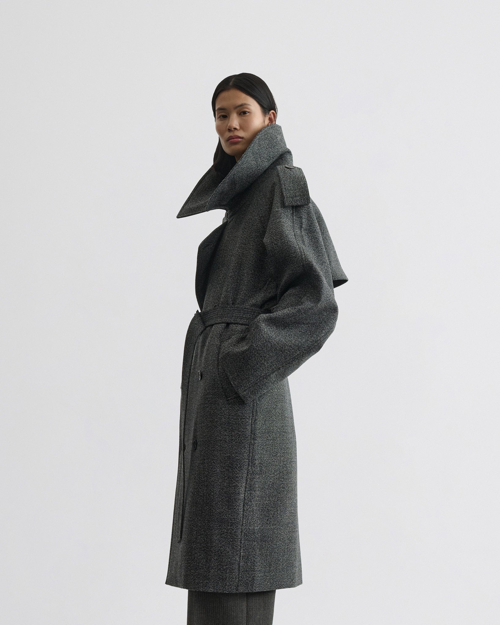 Side view of model wearing padded trench coat in salt and pepper wool.