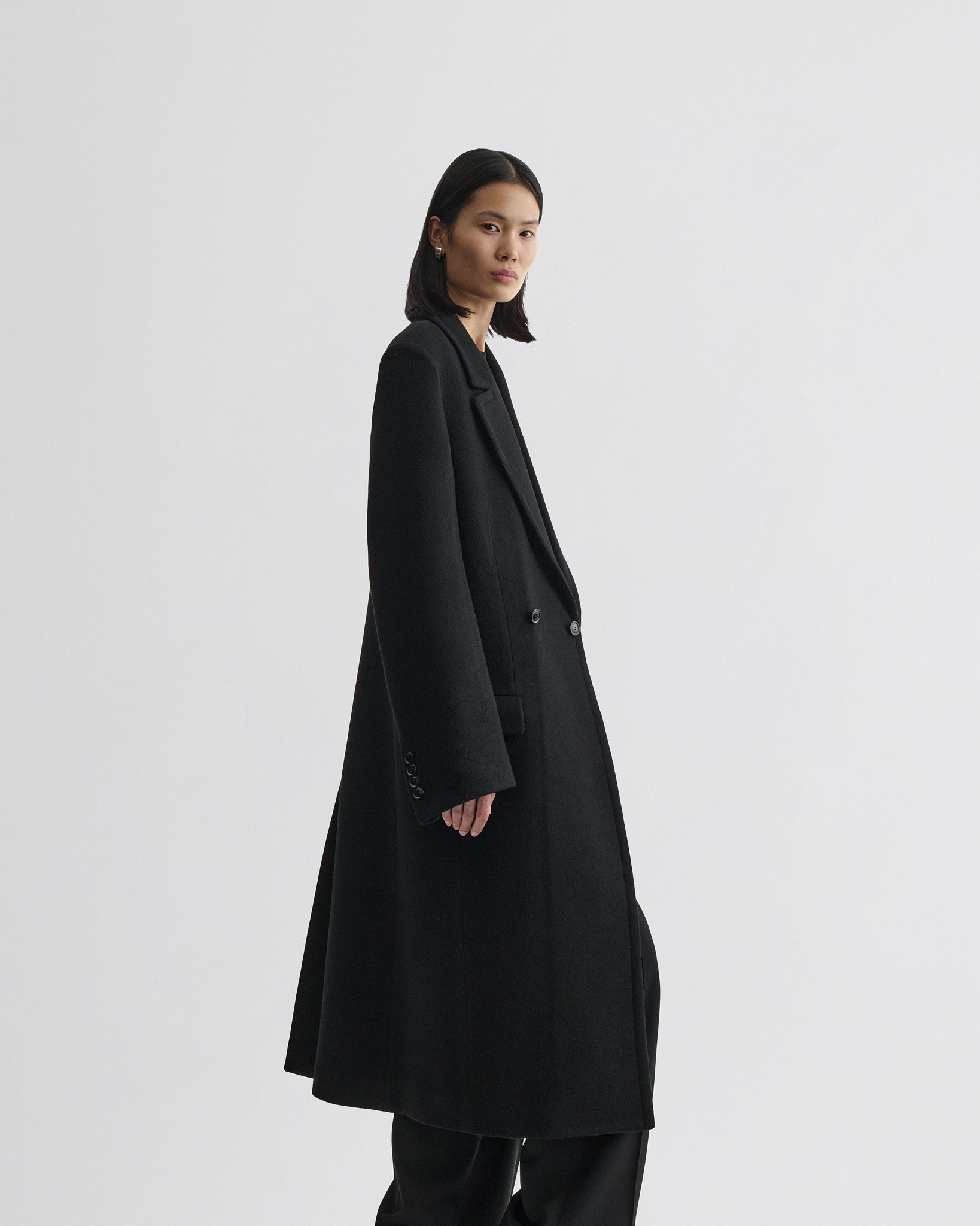 Side view of model wearing classic coat in black cashmere.