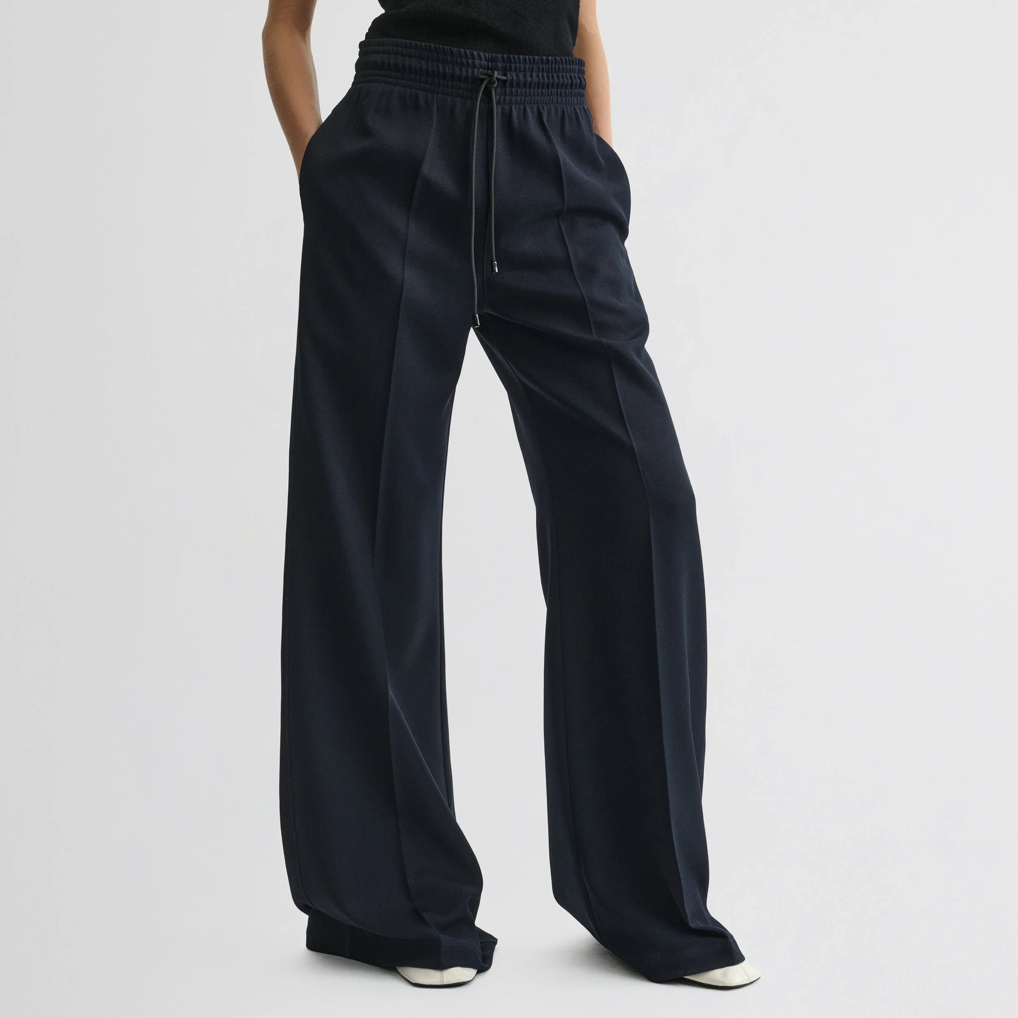 Front view of model wearing track trousers in navy polyester.