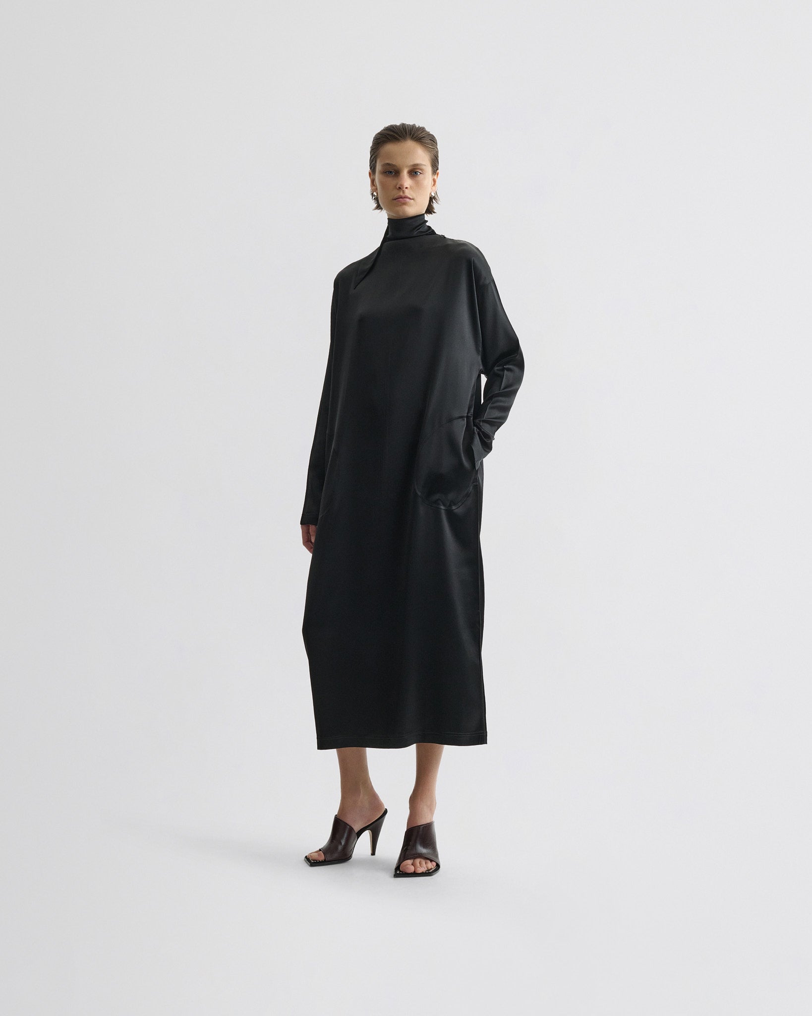 Front view of model wearing liquid high neck dress in black silk.
