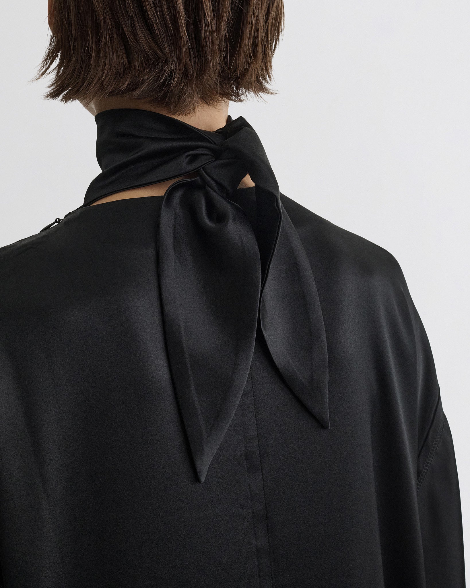 Close up detail view of liquid high neck dress in black silk.