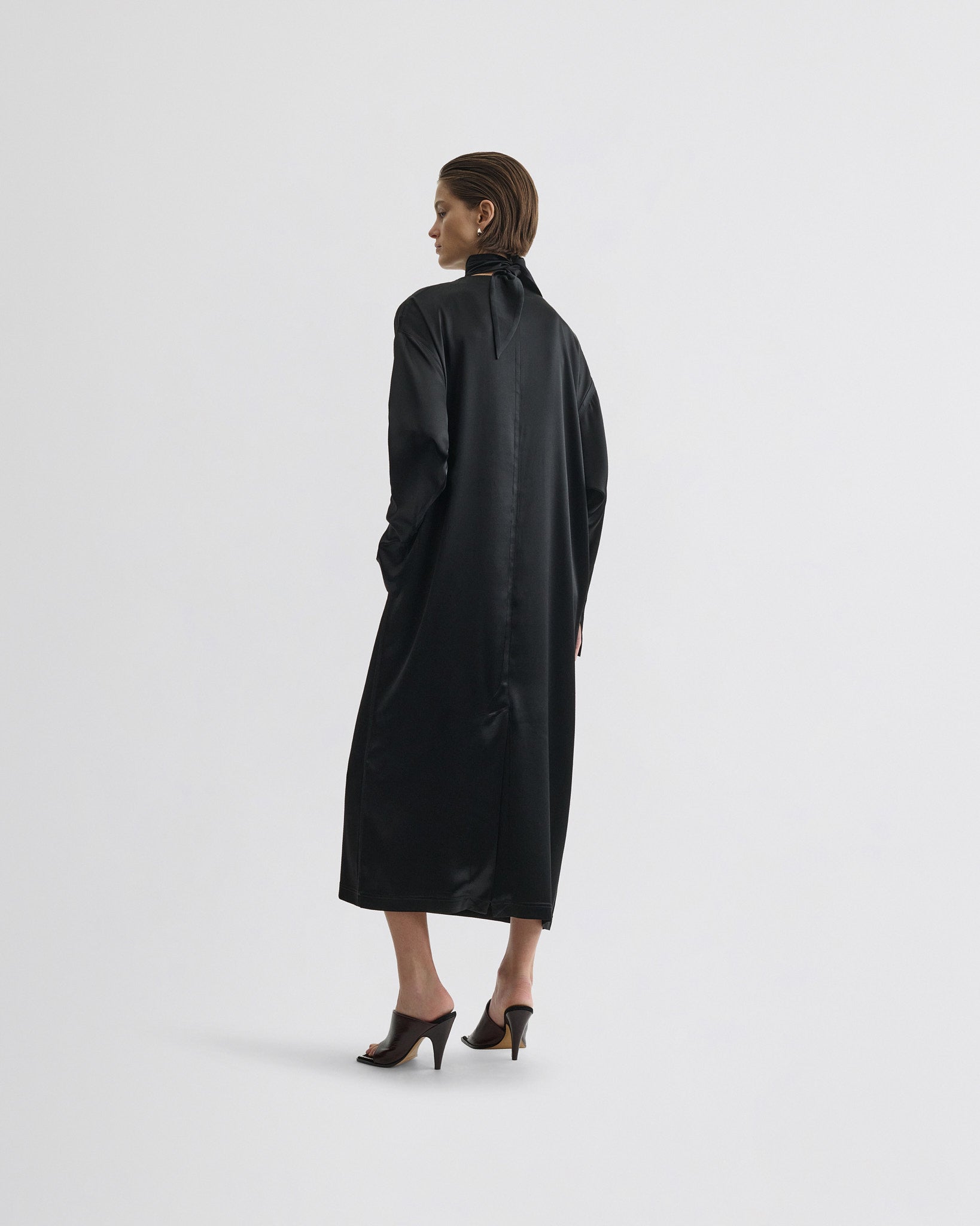 Side view of model wearing liquid high neck dress in black silk.