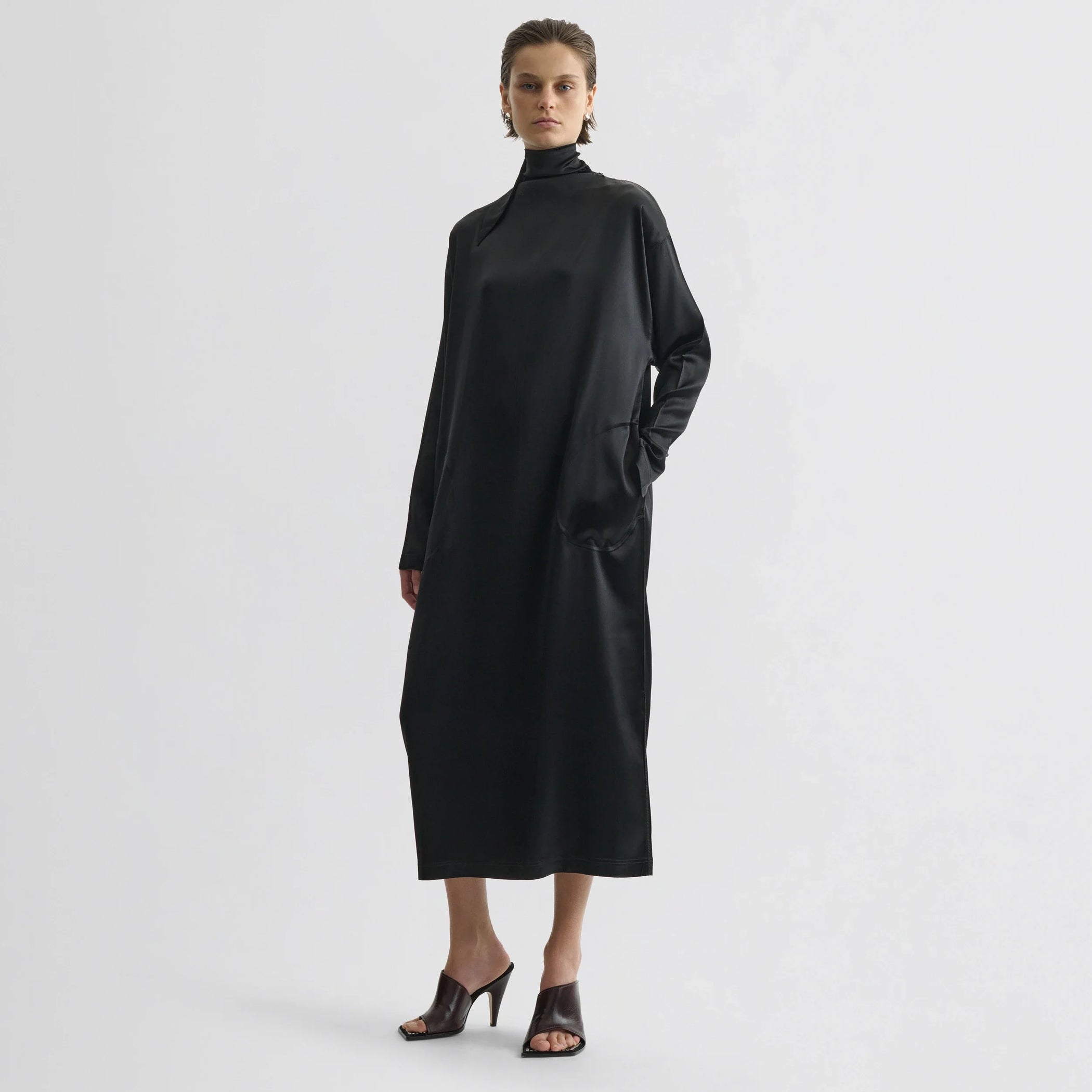 Front view of model wearing liquid high neck dress in black silk.