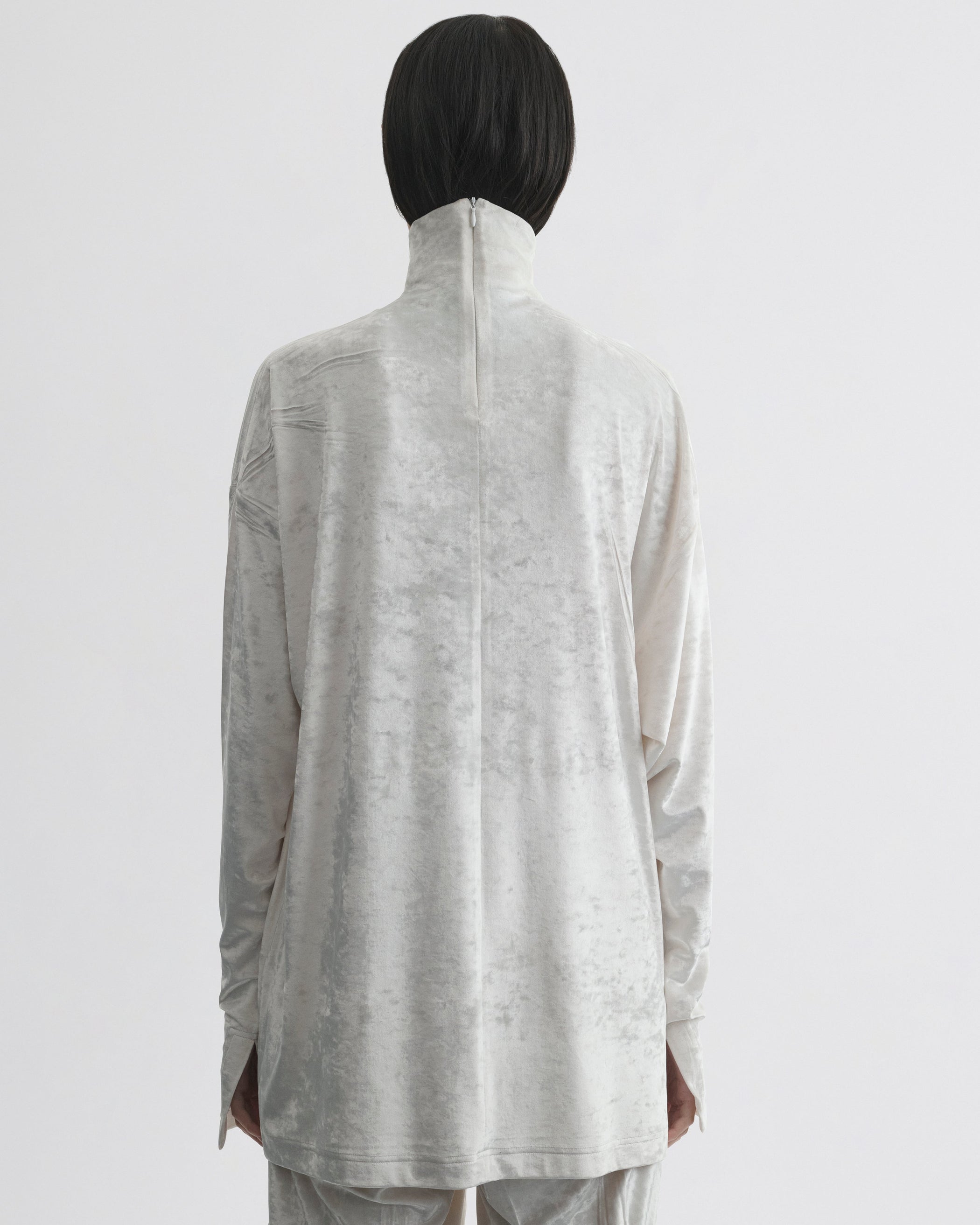 Back view of model wearing LIQUID HIGH NECK TOP in white crushed velvet