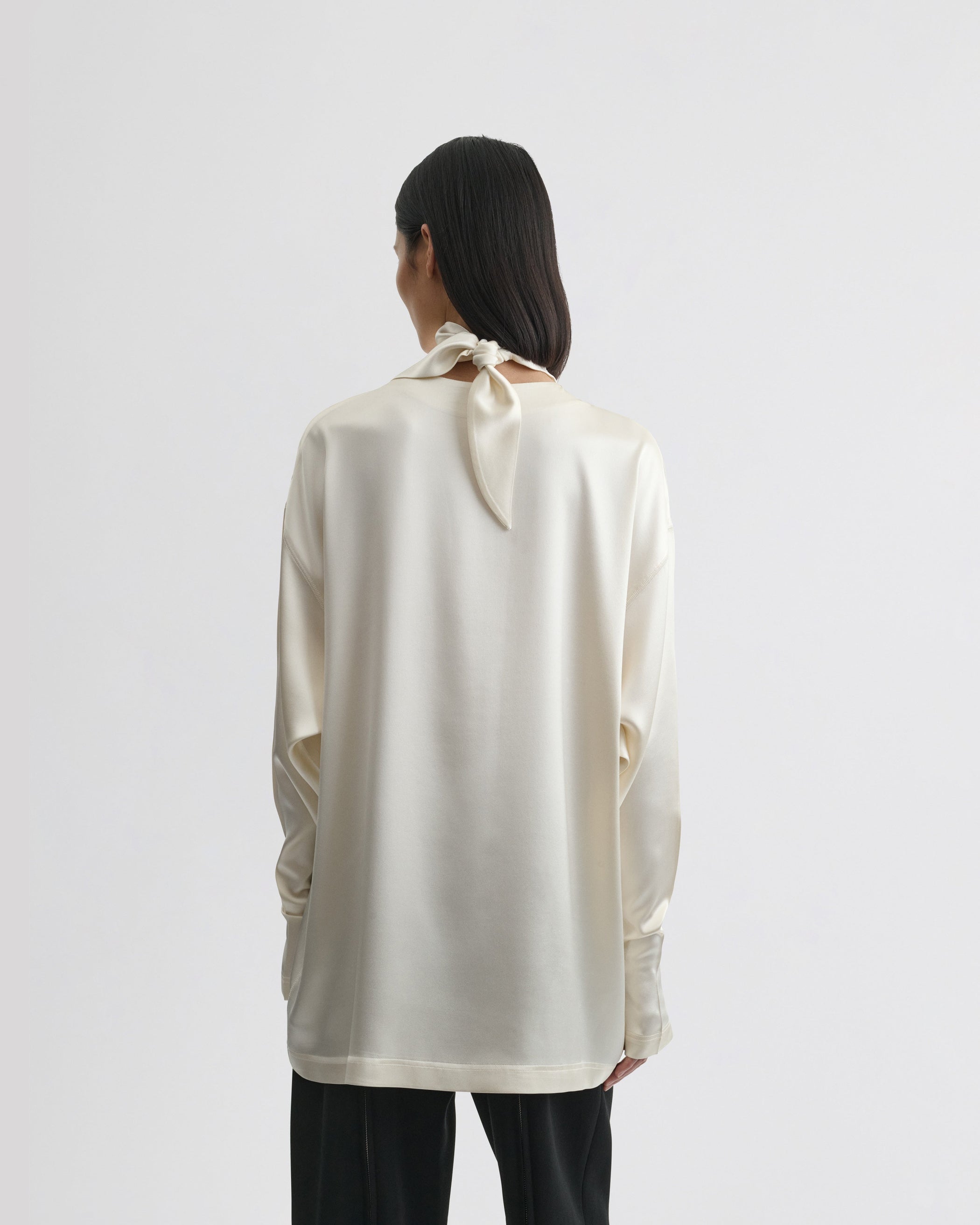 Back view of model wearing LIQUID KNOT COLLAR TOP in cream silk