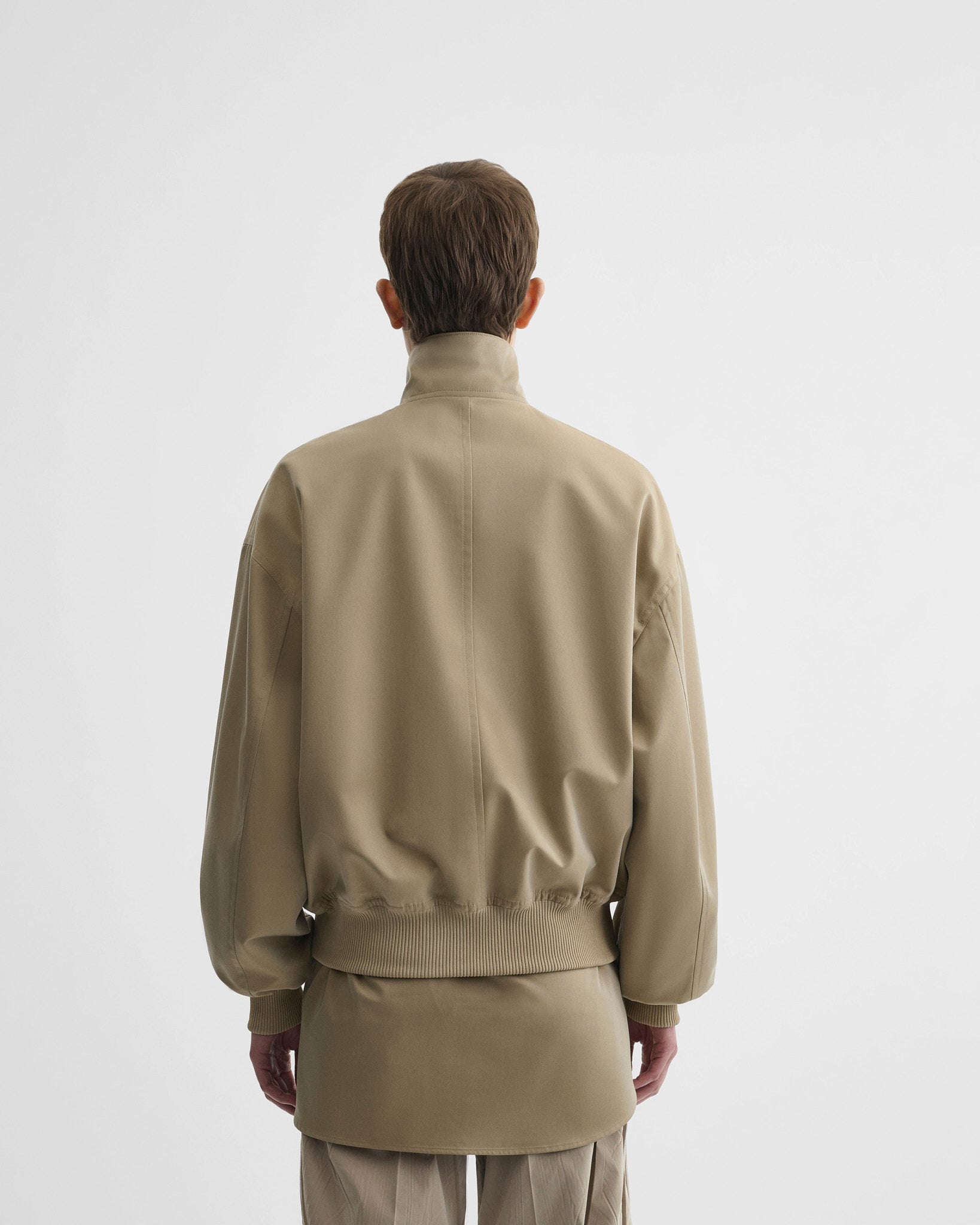Back view of model wearing golf jacket in trench cotton.