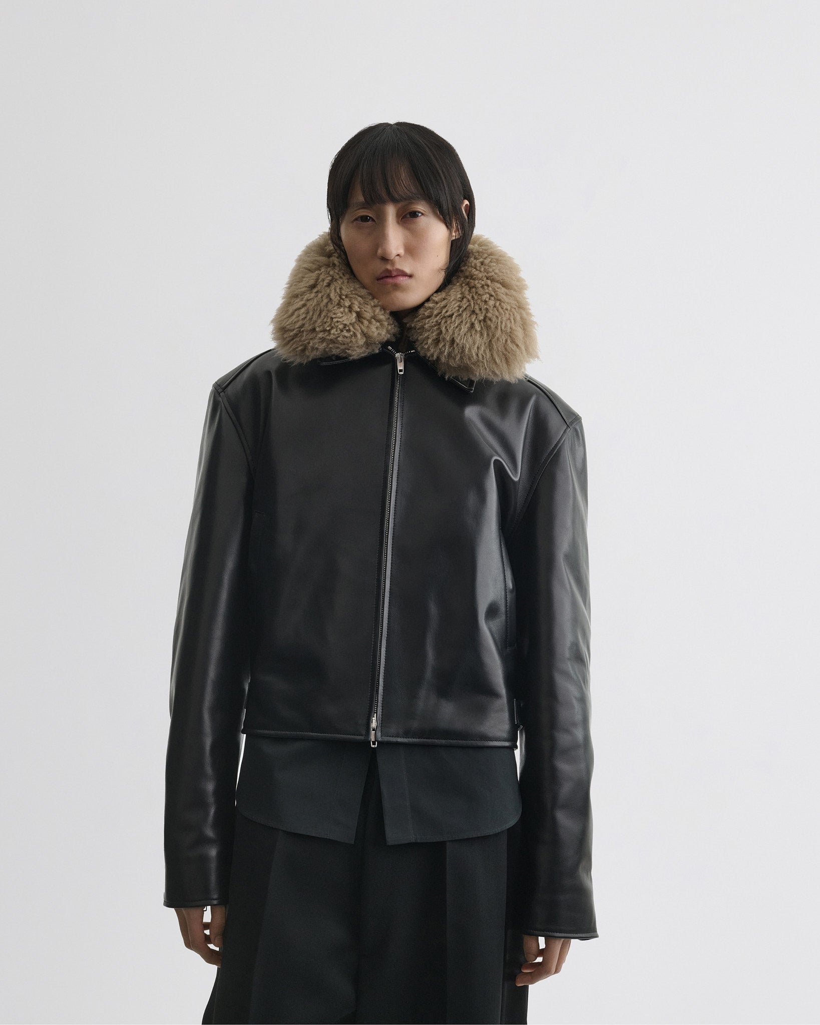 Front view of model wearing cropped aviator jacket in black leather.