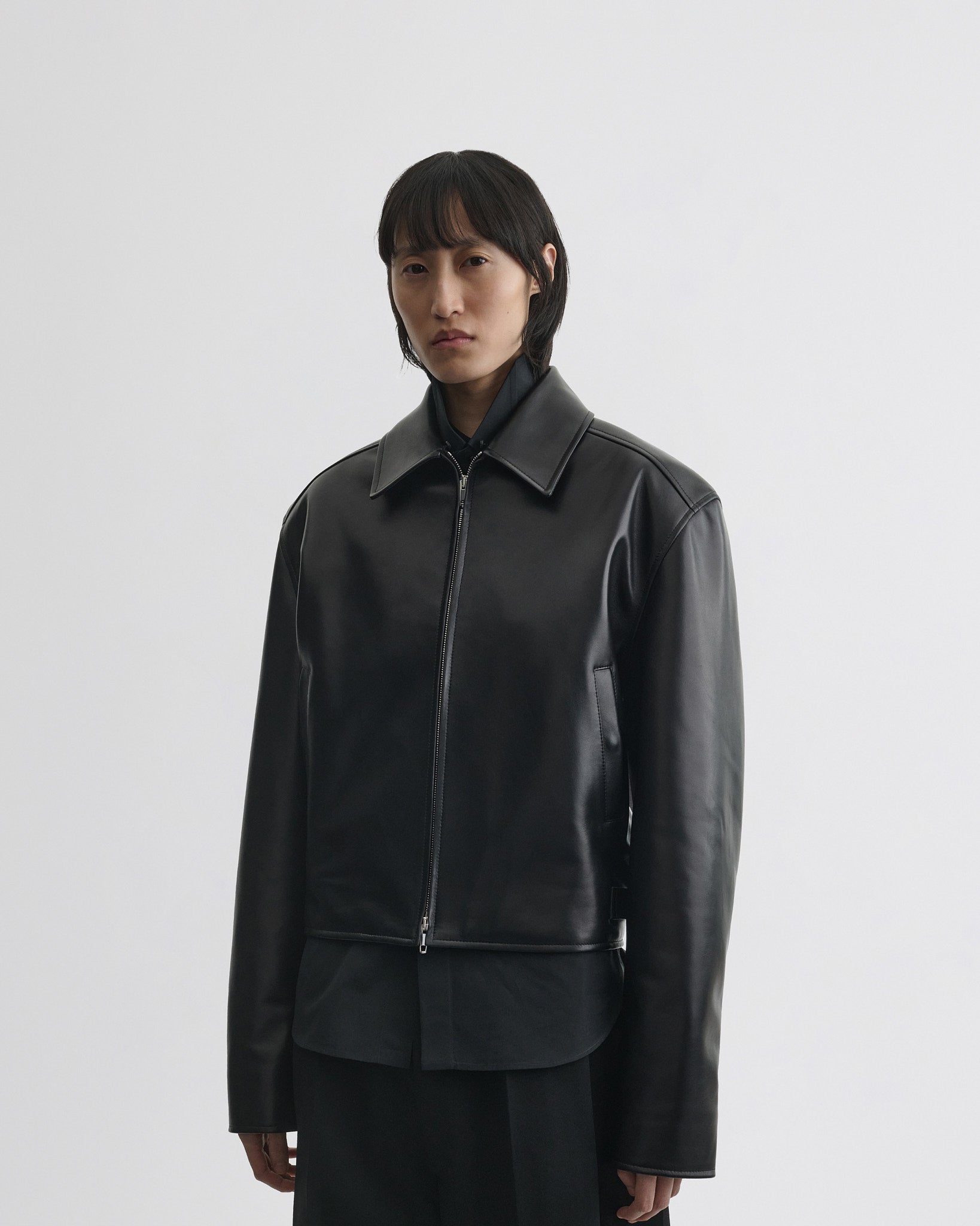 Front view of model wearing cropped aviator jacket in black leather without the collar