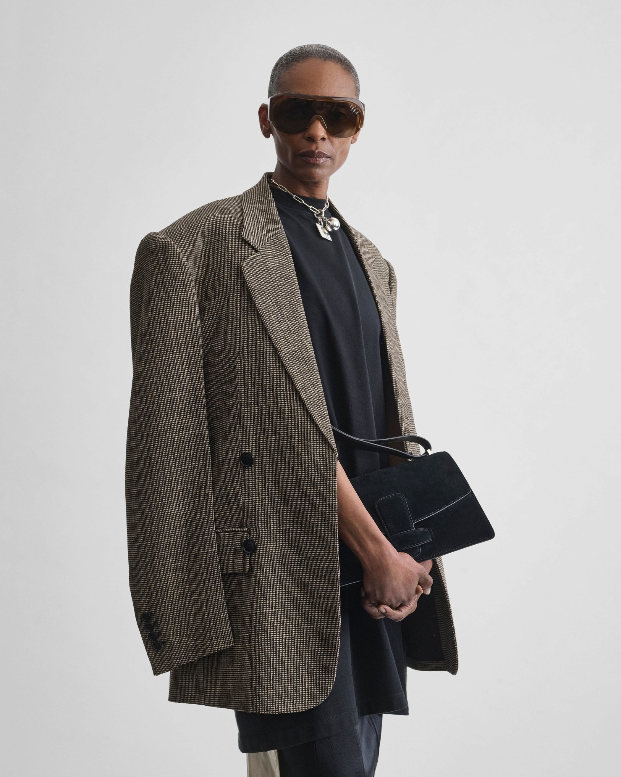 Front view of model holding BAR BAG in black suede