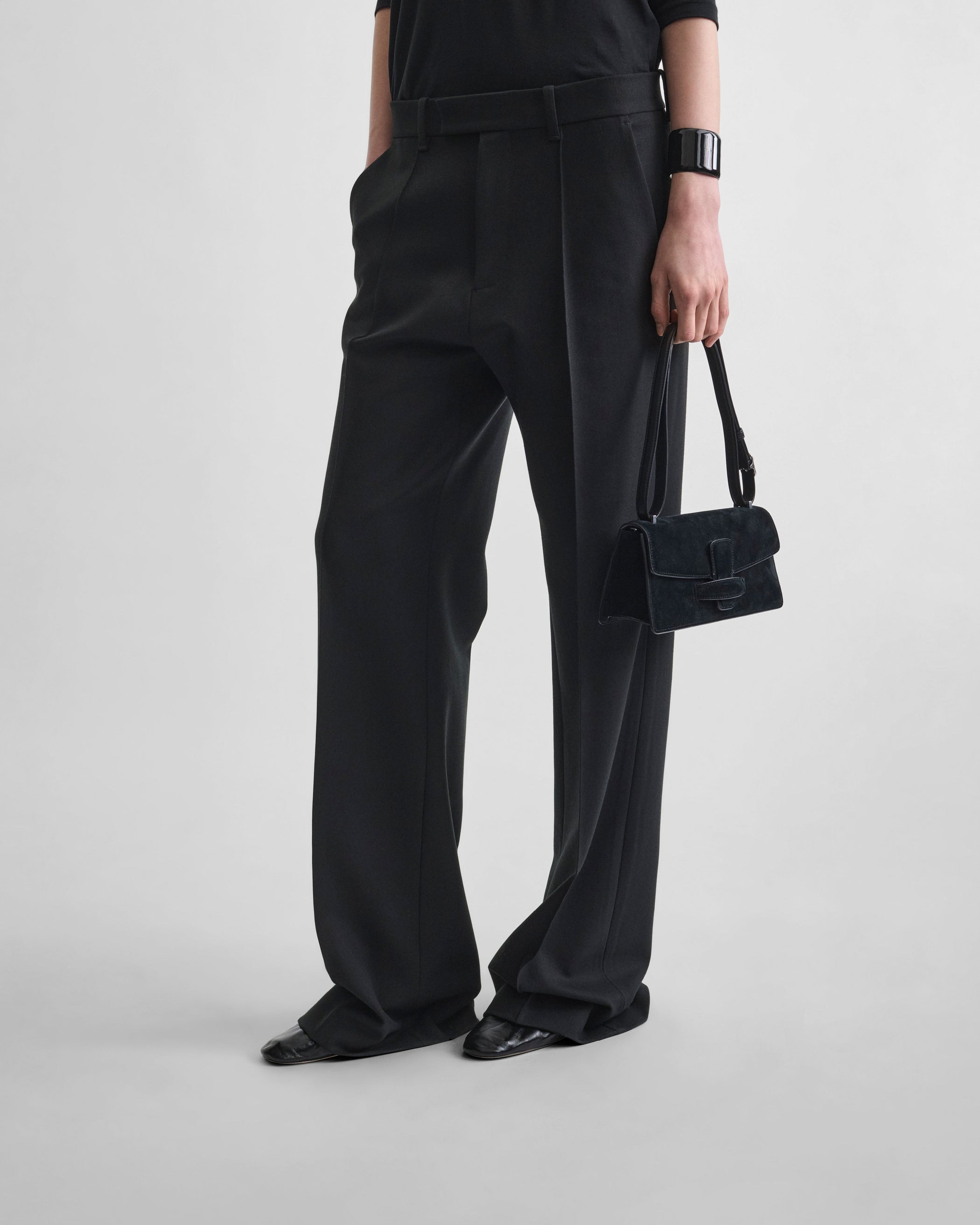 Front view of model holding SMALL BAR BAG in black suede