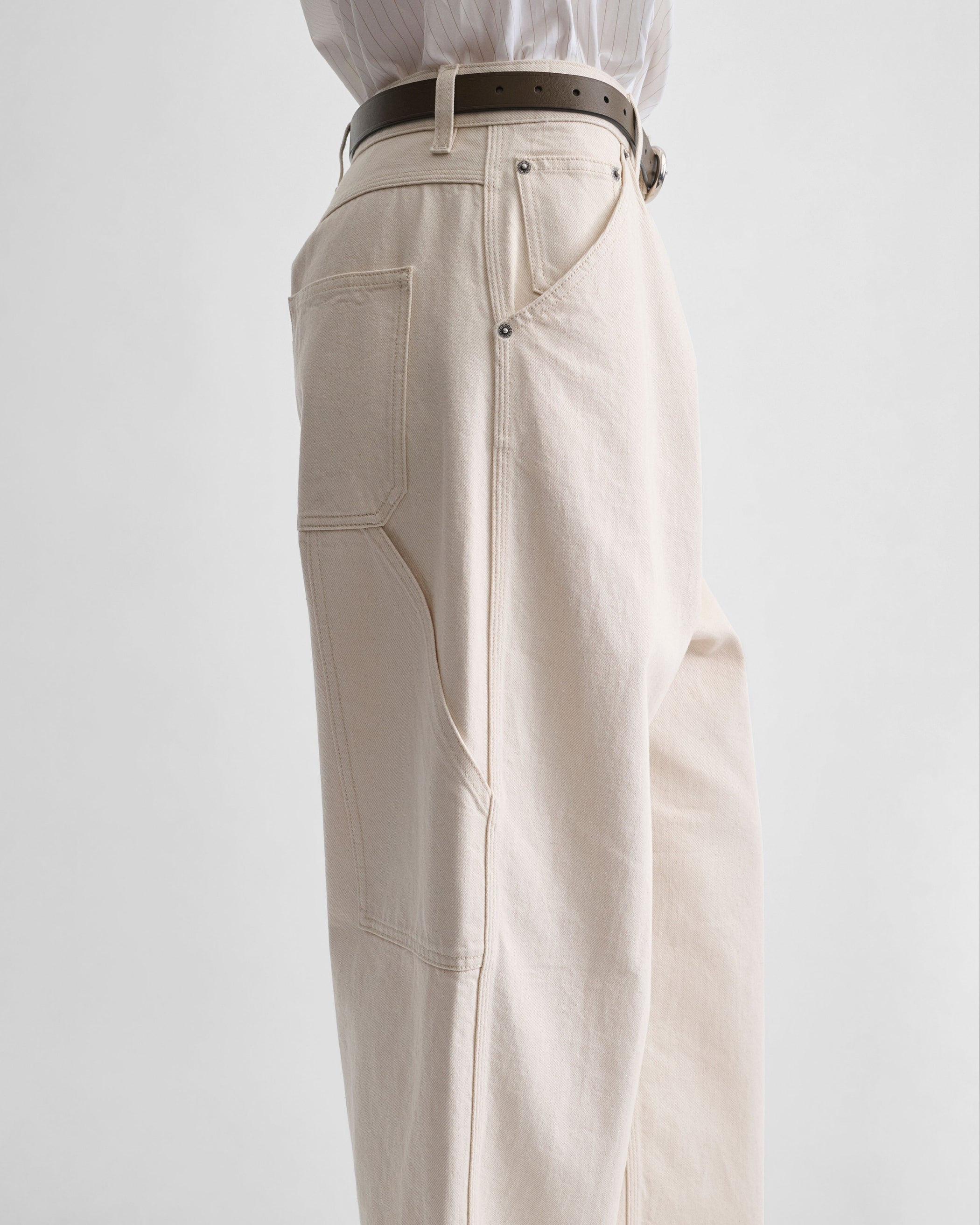 Side view of model wearing CARPENTER JEANS in cream cotton