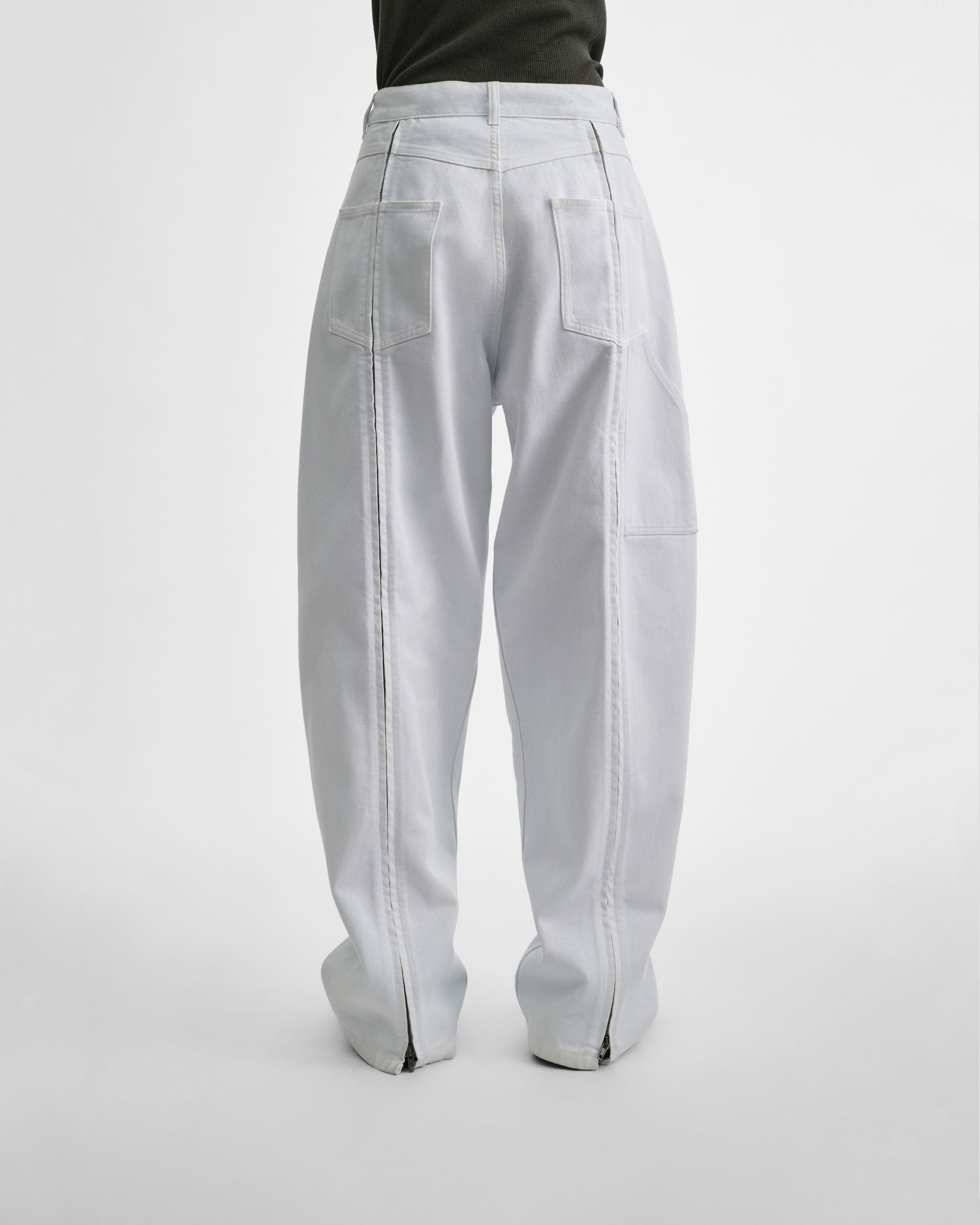 Back view of model wearing RELAXED ZIP JEANS in pale ice blue cotton