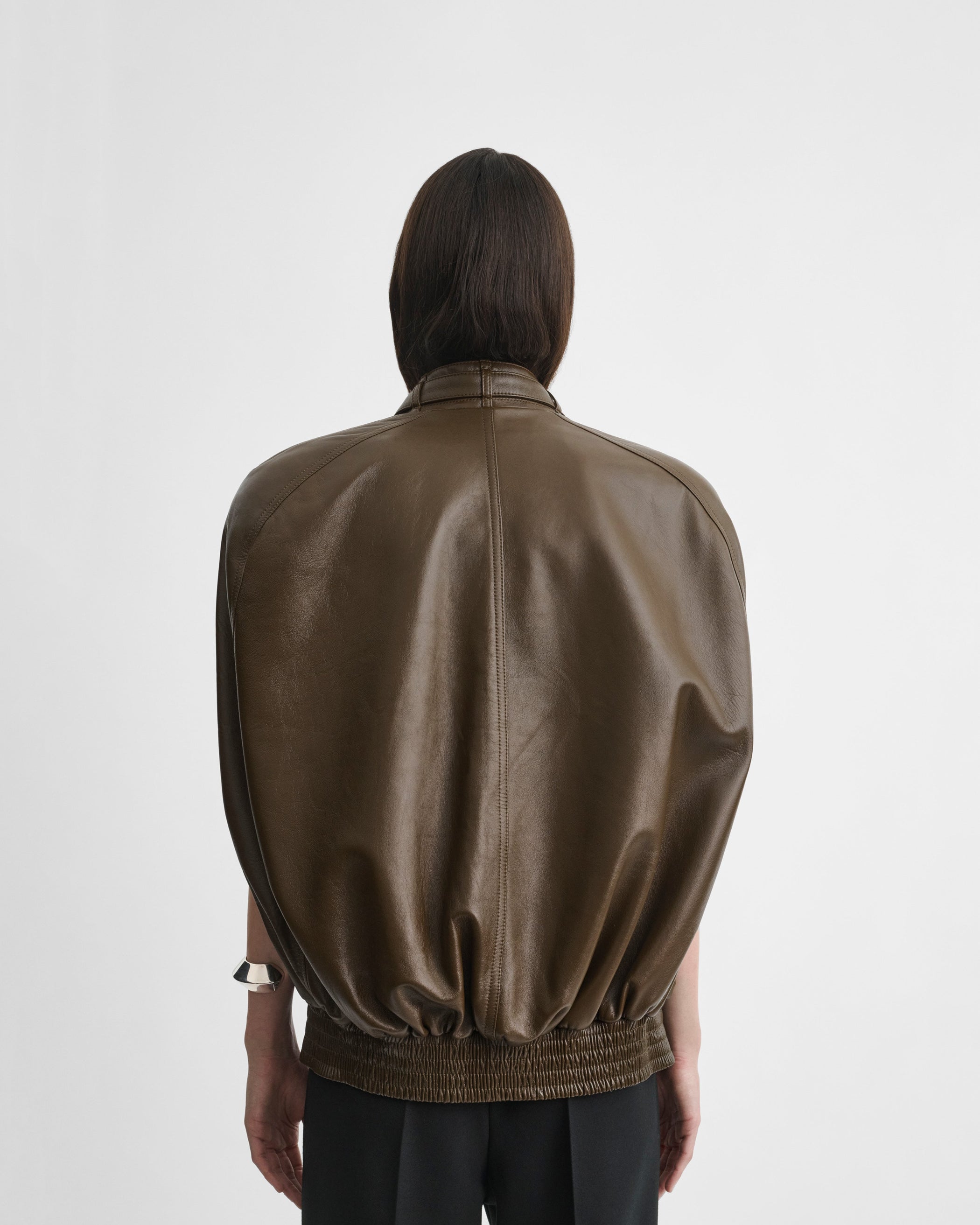 Back view of model wearing CAPE BOMBER in green bronze leather