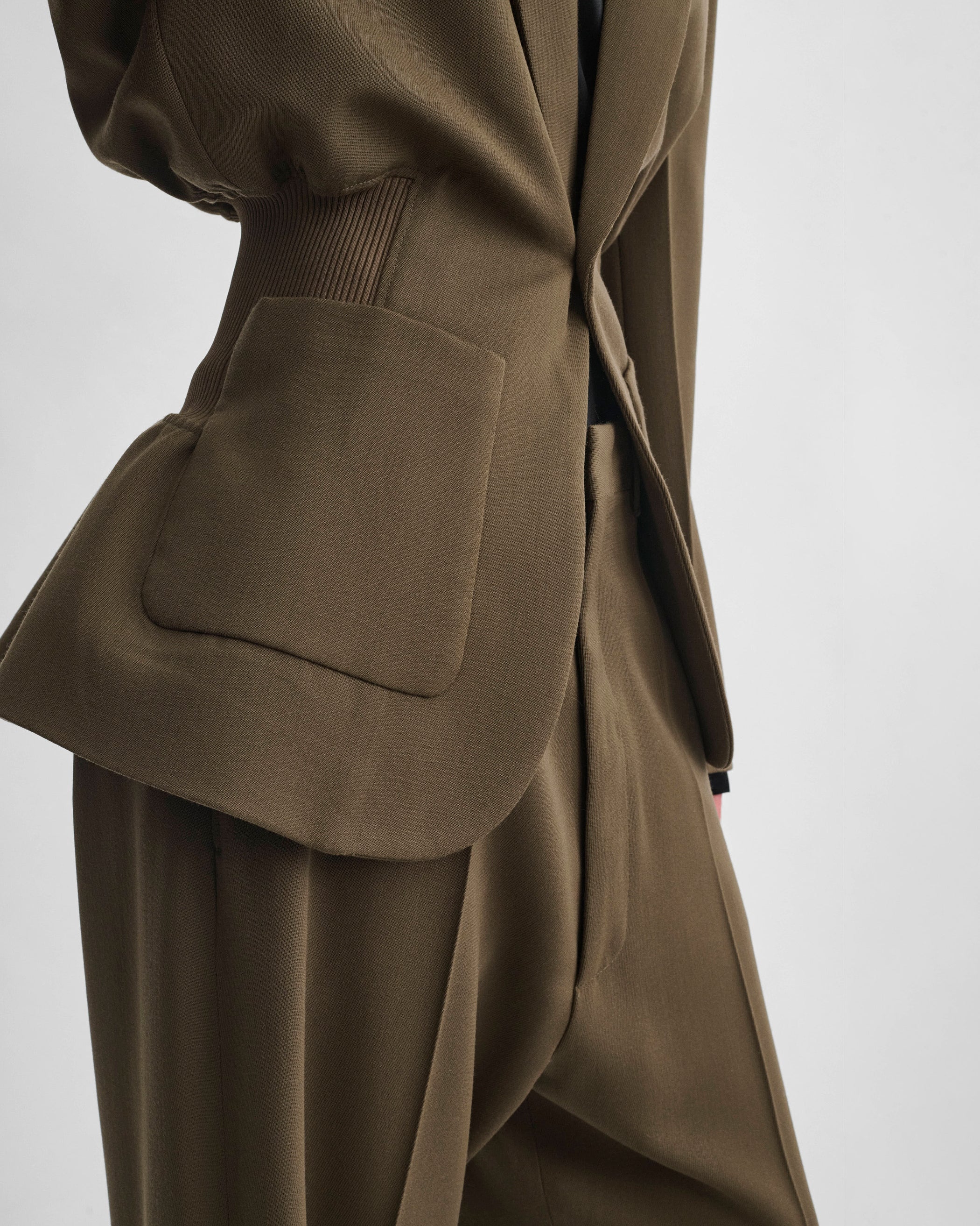 Side detail view of model wearing KICK TAILORED JACKET in shroom wool