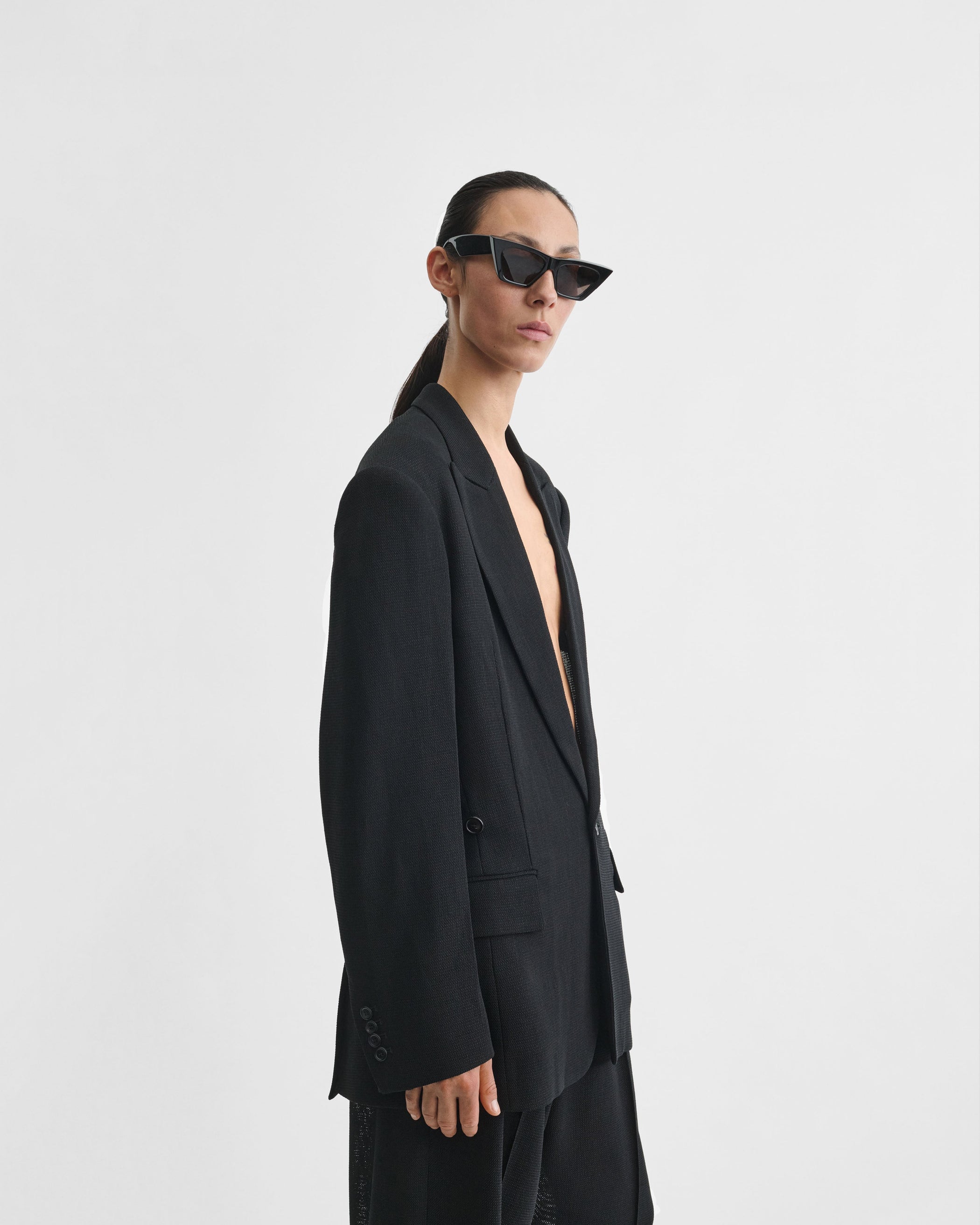 Angled front view of model wearing CINCHED TAILORED JACKET in black woven viscose